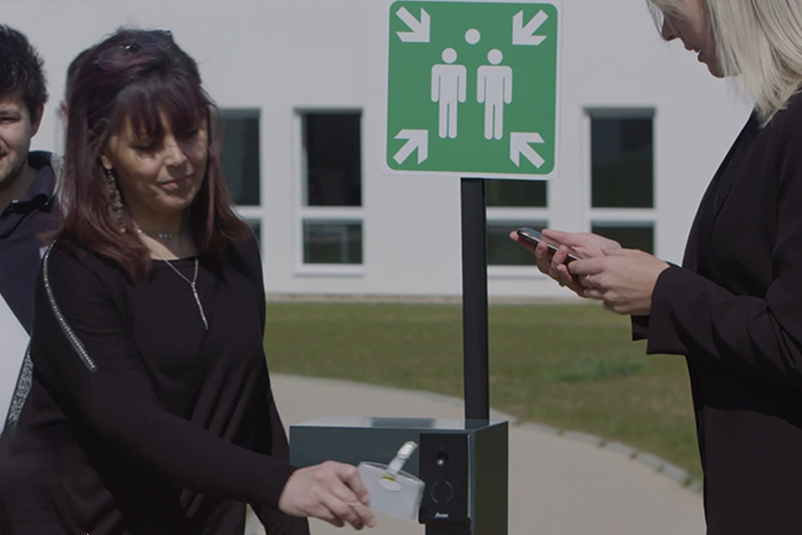 An employee swiping her badge at a Kelio terminal at the meeting point during a fire evacuation