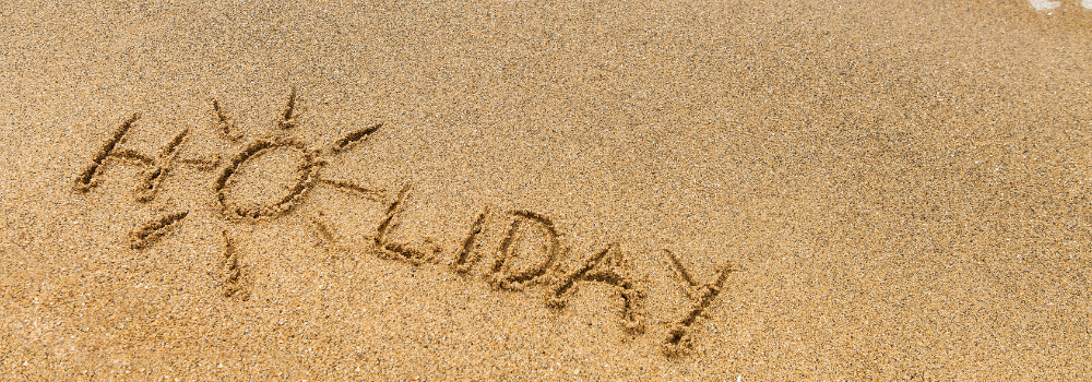 Mot "Holiday" écrit sur le sable