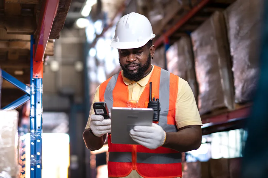 Employee in high visibility vest using a portable device and tablet for monitoring working hours with Kelio