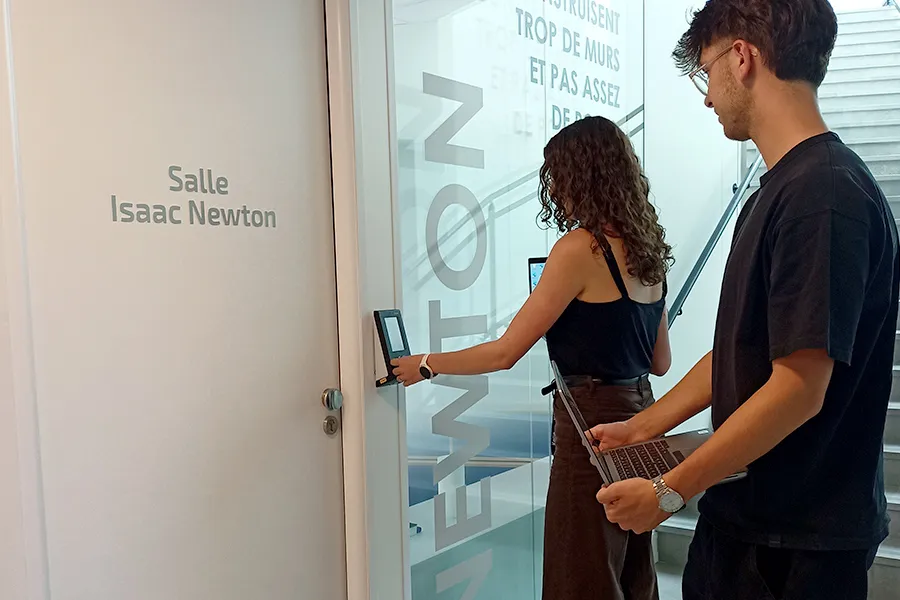 Two employees enter a reserved meeting room by swiping their access badges on the Kelio access reader to open the door